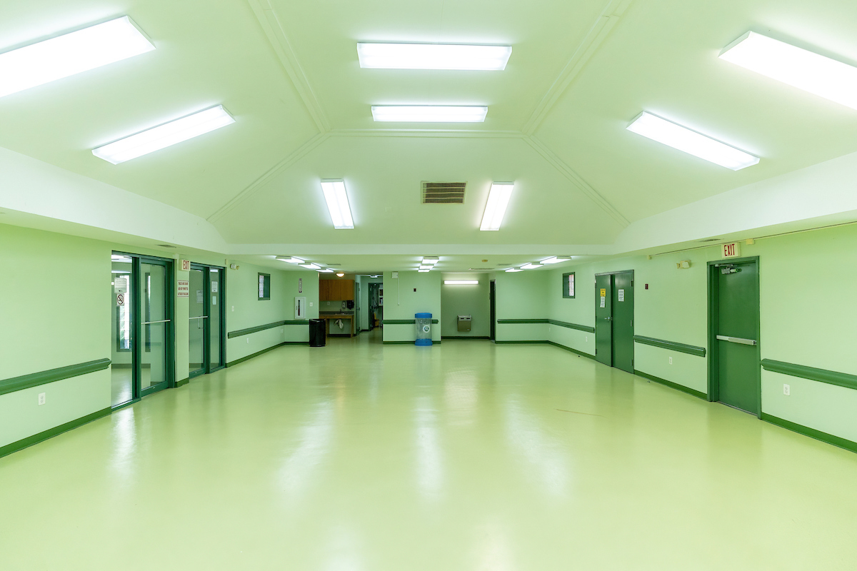 An empty tiled room with a vaulted ceiling and doorways at the far end.