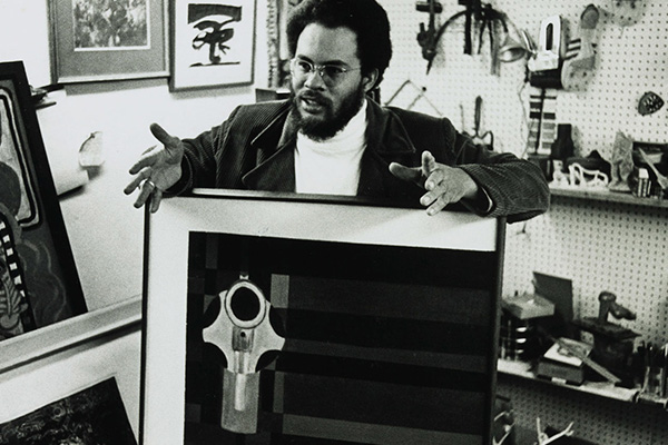 Black-and-white vintage photograph depicting a man standing with a large framed artwork.