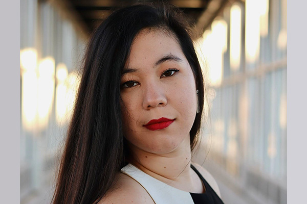 Headshot of a woman in a black and white top with long, dark hair.