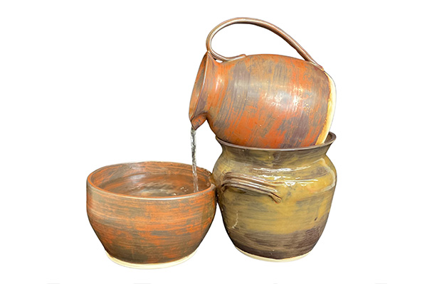 A fountain made of three ceramic vessels, featuring water pouring from a pitcher atop a pot into a bowl.